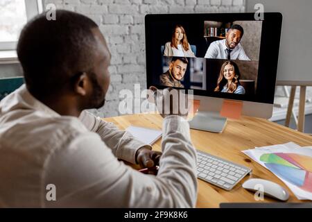 Vue arrière d'un homme d'affaires réussi communiquer avec ses collègues par vidéo réunion, assis à la réception. Un homme afro-américain a un Banque D'Images