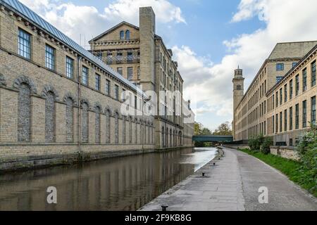 Les bâtiments de Salts Mill des deux côtés du canal Leeds Liverpool à Saltaire, dans le West Yorkshire. Banque D'Images