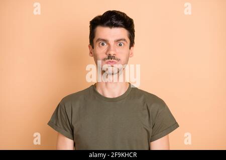 Photo de jeune funky drôle beau hanté choqué homme choqué tenir air respirable, isolé sur fond beige Banque D'Images