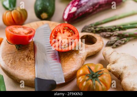 tomates rouges et mûres fraîches sur planche à découper en bois coupées en deux avec couteau. concept de régime de printemps et de nutrition végétalienne biologique Banque D'Images
