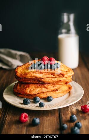 Vue rapprochée d'une assiette beige antique avec poêle frite de myrtilles et framboises sur une table en bois sombre. Torrijas espagnoles Banque D'Images