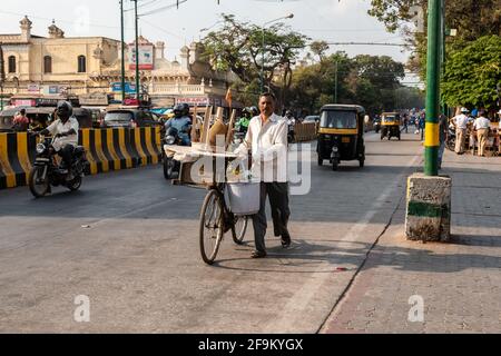 Mysuru, Karnataka, Inde - janvier 2019 : un vendeur de rue marchant avec son vélo sur une route très fréquentée dans la ville de Mysore. Banque D'Images