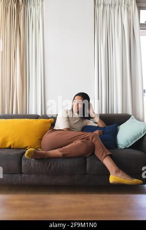 Bonne femme transgenre de race mixte se détendant dans le salon assis sur le canapé souriant Banque D'Images