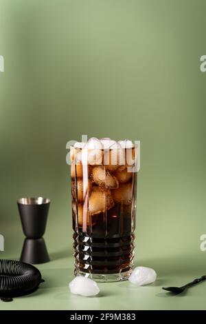Boisson non alcoolisée Coca-Cola ou cocktail Cuba libre dans un verre avec des glaçons isolés sur fond vert Banque D'Images