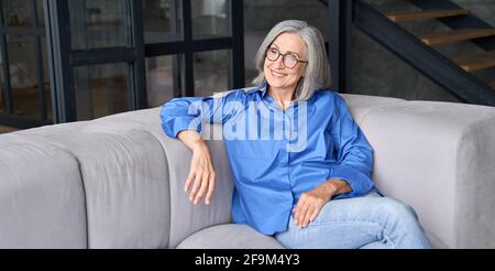Femme âgée de milieu de gamme dans des lunettes qui profite du bien-être et de la vision de l'avenir. Banque D'Images