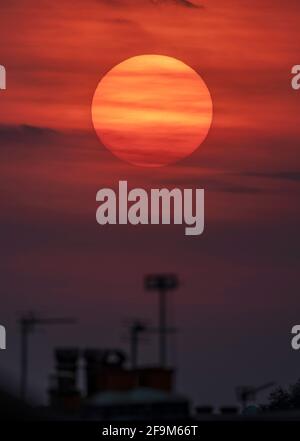 Londres, Royaume-Uni. 19 avril 2021. Sunspot groupe AR2816 peut être vu vers le coucher du soleil au milieu à gauche du centre sur le disque du soleil comme il coule à travers les nuages brumeux après une journée de températures chaudes à Londres. Cette région de tache solaire active grésille actuellement avec des éruptions solaires. Crédit : Malcolm Park/Alay Live News. Banque D'Images