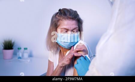 Médecin donnant le vaccin Covid à une femme âgée avec un masque facial. Vaccination et immunisation pendant le coronavirus. Photo de haute qualité Banque D'Images