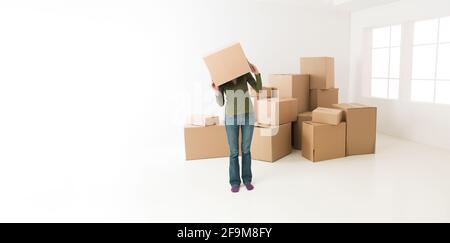 Déménagement dans la nouvelle maison, femme, s'amusant de se cacher la tête dans la boîte en carton Banque D'Images
