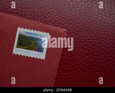 Enveloppe rouge avec timbre canadien sur fond clair. Banque D'Images