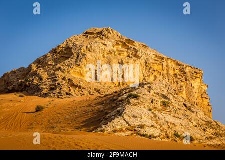 Fossil Rock formation de roches calcaires dans le désert, avec des dunes de sable autour, Sharjah, Émirats arabes Unis. Banque D'Images