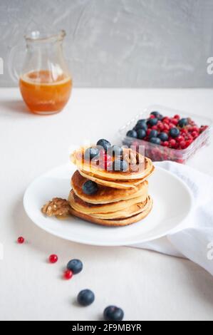 Crêpes délicieuses fraîchement cuites avec du miel, des noix, du miel, des framboises et des myrtilles pour le petit déjeuner. Banque D'Images