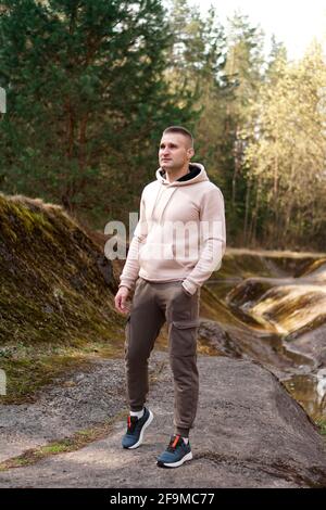 Un jeune homme en costume confortable se promène dans la forêt au bord de la rivière. Banque D'Images