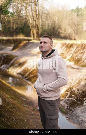 Un jeune homme en costume confortable se promène dans la forêt au bord de la rivière. Banque D'Images