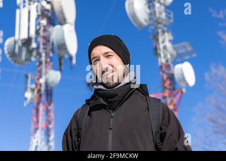 Une photo très claire d'un visiteur se tenant devant des tours de base cellulaire, avec plusieurs antennes, fournissant des services mobiles 3G et 4G Banque D'Images