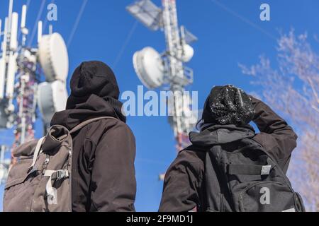 Tourné de deux touristes regardant vers le haut une grande infrastructure de tours de télécommunication, avec les antennes jointes pour convertir les signaux. Banque D'Images