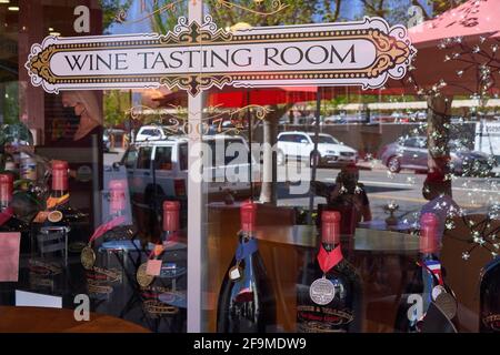 Étiquette de la salle de dégustation de vin et bouteilles de vin affichées sur une fenêtre, réflexions de la rue et deux personnes assises à une table à Healdsburg, Californie. Banque D'Images