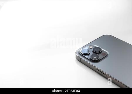 Détail d'un Apple iPhone 12 Pro Max face vers le bas sur un arrière-plan flanqué avec espace pour la copie, montrant ses trois objectifs d'appareil photo, horizontal