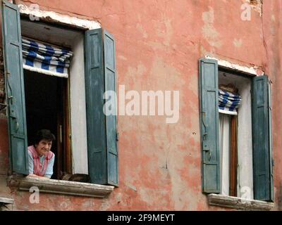 Venise, Italie. Une femme locale assise à la fenêtre. Banque D'Images