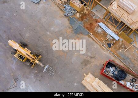 Vue aérienne des planches en bois de l'empileur de chariots élévateurs et des bennes à ordures construction sur l'encadrement d'appartement d'une nouvelle maison en construction Banque D'Images