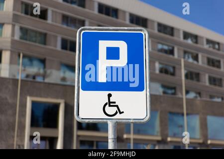 panneau de signalisation bleu avec symbole fauteuil roulant, parking handicapés, seules les personnes autorisées avec une pièce d'identité valide sont autorisées à se garer ici, le jour, avec Banque D'Images