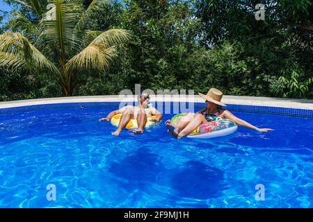 Couple heureux avec anneaux gonflables dans la piscine Banque D'Images
