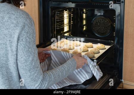 Vue arrière de la jeune femme prenant des biscuits de noix de coco de la four à Banque D'Images
