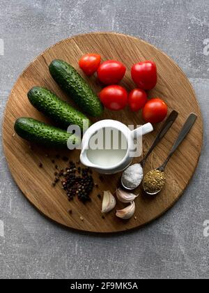 tomates cerises, concombres, ail, crème aigre, épices sur une planche de bois Banque D'Images