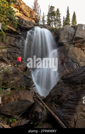 Une randonneur femelle se tenant à côté des chutes d'Ouzel situées dans le Bassin sauvage du parc national des montagnes Rocheuses Banque D'Images