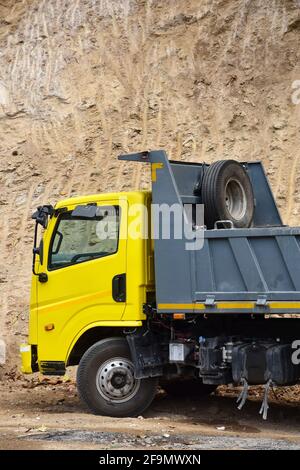 Camion avec cabine jaune et mur de boue avec corps gris Banque D'Images