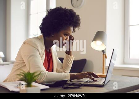 Une jeune femme d'affaires afro-américaine confuse et réfléchie regarde un ordinateur portable Banque D'Images