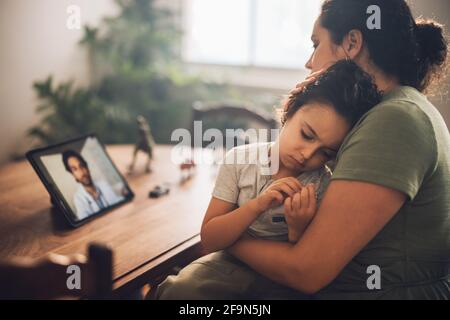 Mère avec son fils ayant un appel vidéo avec un médecin numérique à la maison. Femme prenant des conseils d'un médecin pendant la télémédecine pour son fils malade. Banque D'Images