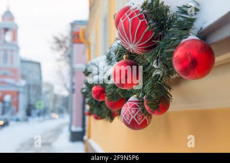 Décorations de Noël affichées à l'extérieur par fenêtre. Branches de sapin enneigé de Noël élégantes avec boules festives sur un rebord de fenêtre dans la rue d'un festif Banque D'Images