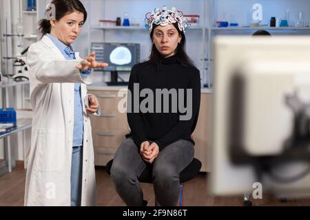 Médecin chercheur oreillette EEG analysant l'évolution du patient après traitement contre une maladie du système nerveux. Équipe de scientifiques travaillant tard dans la nuit en laboratoire de recherche neurologique. Banque D'Images