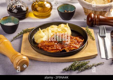 Côtelettes de porc rôties nappées de ragoût d'oignon et servies avec de la purée pommes de terre Banque D'Images