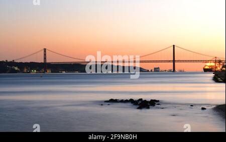 Coucher de soleil sur le Tage et le pont suspendu du 25 avril. Banque D'Images