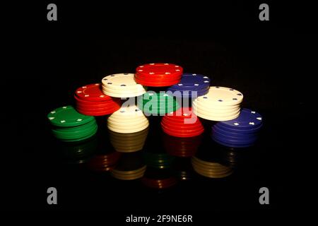 Piles de jetons de poker isolés sur le noir avec des réflexions Banque D'Images