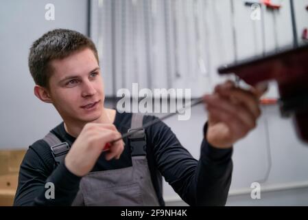 Portrait d'un jeune spécialiste en débosselage concentré sur la réparation automobile station Banque D'Images