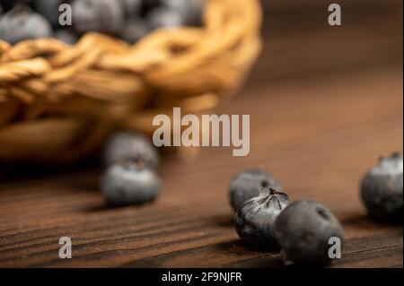 Bleuets frais dans un panier en osier sur une table en bois. Récolte, petit déjeuner du village. Mise au point sélective en gros plan. Banque D'Images