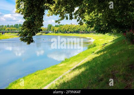 rive de la rivière uzh. magnifique paysage urbain en été. vue de dessous l'ombre d'un arbre de linden branches. pont au loin Banque D'Images