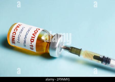 Macro-injection d'un flacon de vaccin antiviral avec seringue pour la vaccination contre le virus Covid-19. Isolé sur fond bleu avec espace de copie pour le texte. Fermer Banque D'Images