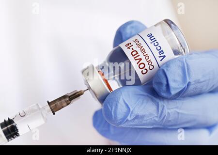 Gros plan des mains du médecin dans des gants en latex remplissant la seringue avec le nouveau vaccin Covid-19 du flacon. Gros plan, espace de copie, arrière-plan. Banque D'Images