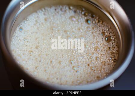 Gros plan café coloré et avoine végétale bulles de mousse de lait à l'intérieur de thermos en acier inoxydable, shaker, macro boisson chaude Banque D'Images