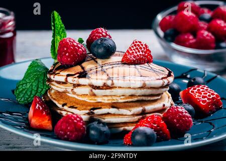 gros plan d'une assiette de crêpes avec sirop de caramel, fruits frais et feuilles de menthe. petit pot de fond de confiture. mise au point sélective Banque D'Images