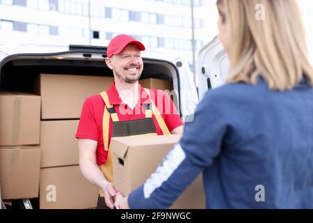 Homme de messagerie en uniforme donnant à la femme boîte en papier de la voiture Banque D'Images