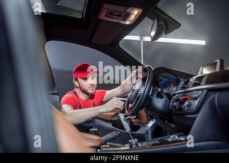 Homme dans une salopette qui effectue l'entretien de la voiture Banque D'Images