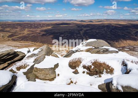 Pierres et neige de Gritstone sur le bord nord de Kinder Scout dans le parc national de Peak District. Vue sur les landes Pennine. Banque D'Images