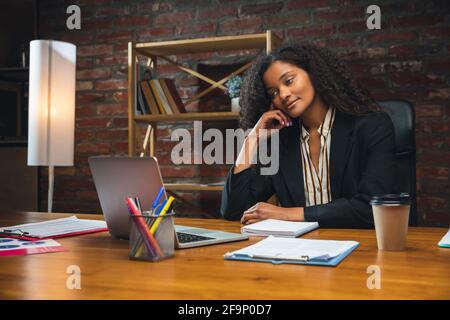 Jeune femme travaillant dans un bureau moderne utilisant des appareils et des gadgets. Création de rapports, d'analyses, de tâches de traitement de routine Banque D'Images