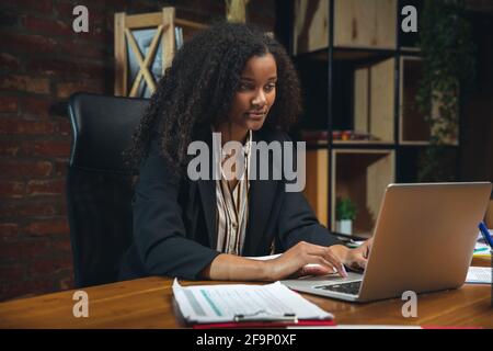 Jeune femme travaillant dans un bureau moderne utilisant des appareils et des gadgets. Création de rapports, d'analyses, de tâches de traitement de routine Banque D'Images