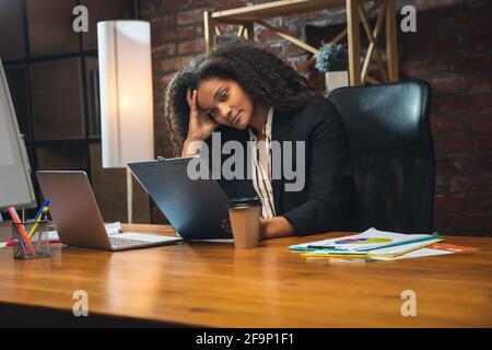 Jeune femme travaillant dans un bureau moderne utilisant des appareils et des gadgets. Création de rapports, d'analyses, de tâches de traitement de routine Banque D'Images