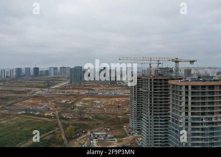 Grues de construction debout près de bâtiments inachevés à plusieurs étages Banque D'Images